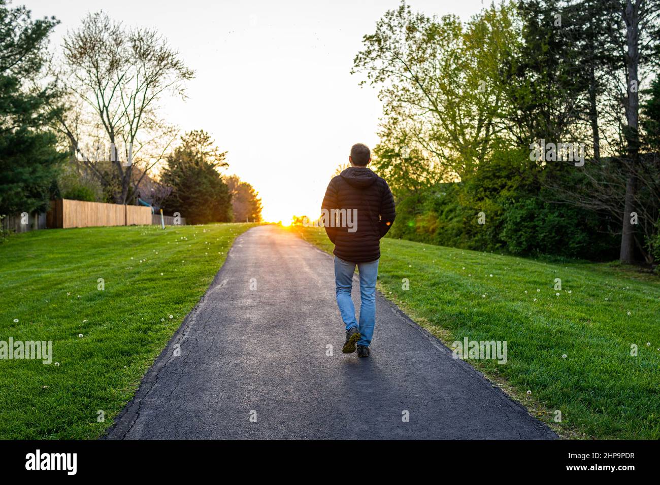 Passeggiata Sugarland Run Stream Valley Trail a Herndon, contea di Fairfax in Virginia primavera con strada lastricata e silhouette di uomo a piedi verso il tramonto Foto Stock