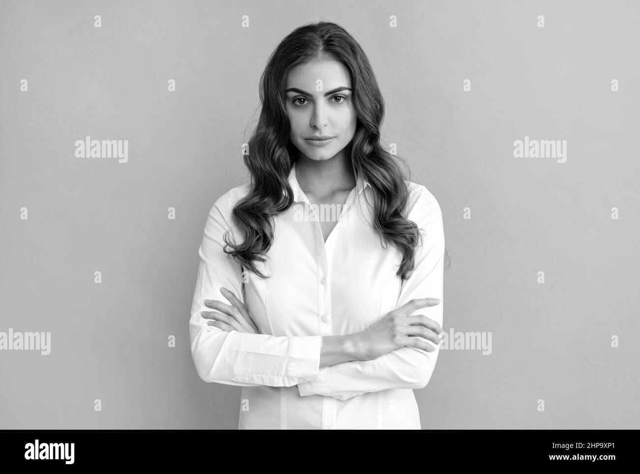 Donna di affari seria e sicura tiene le braccia incrociate grigio, fiducia Foto Stock