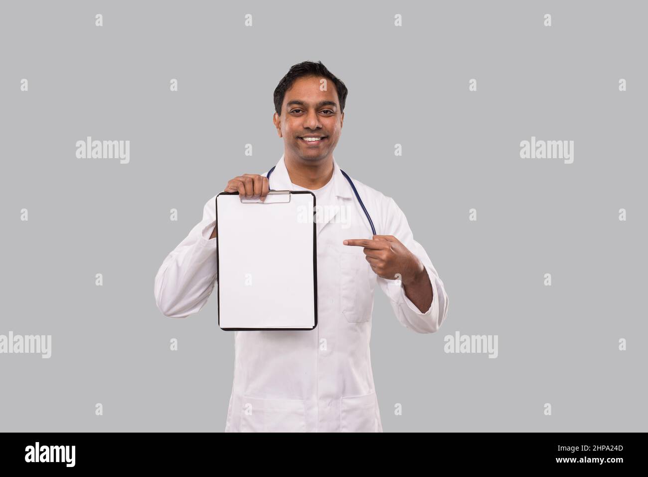 Medico che punta alle Clipboard isolato. Gli appunti vuoti del medico dell'uomo indiano nelle mani Foto Stock