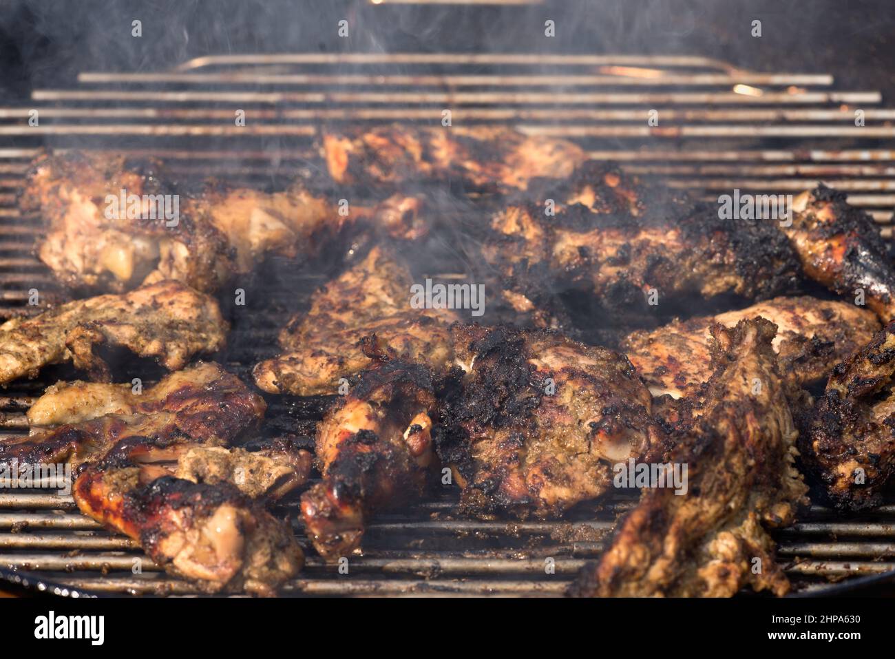 La grigliatura tradizionale giamaicana piccante di pollo jerk con oltre il fuoco di legna. Foto Stock