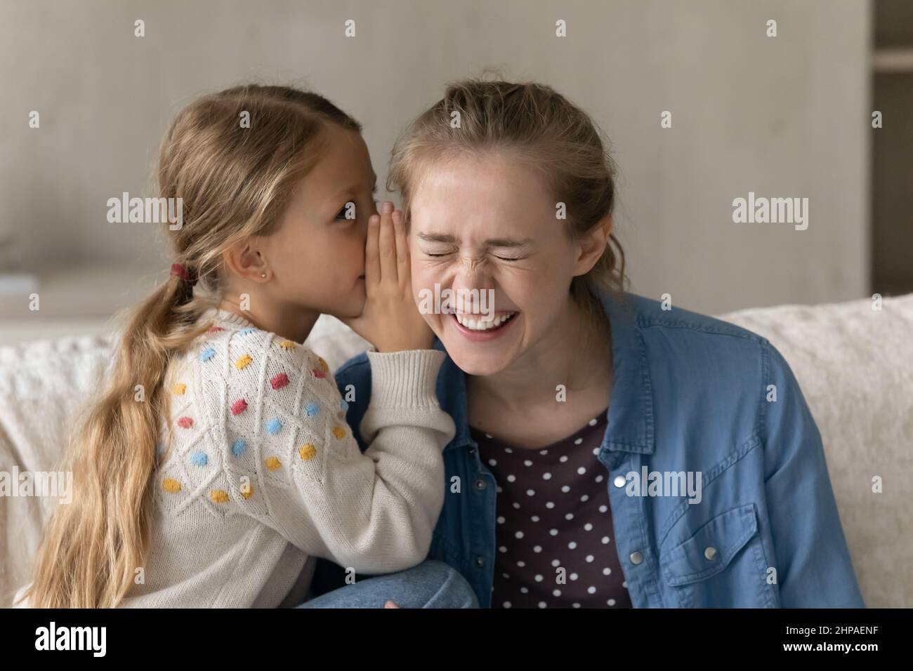 Cute capretto che dice segreto a sorridere felice sorella anziana, anny Foto Stock