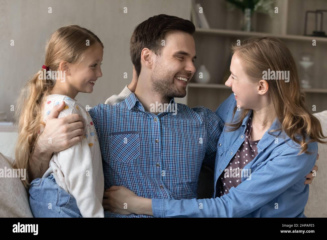 Felice moglie e figlia carina abbracciando marito e padre grati Foto Stock