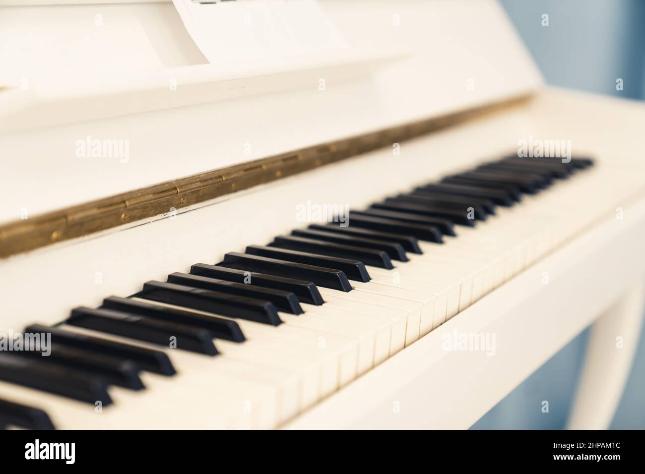 primo piano di un elegante pianoforte bianco in piedi al chiuso. Foto di alta qualità Foto Stock