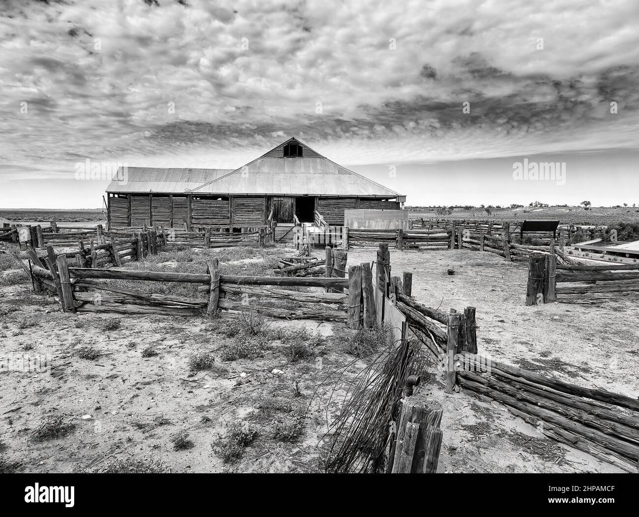 Annata scala di grigi Mungo lago shep capannone di lana con recinzione in legno nella parte esterna dell'Australia su pianure aride. Foto Stock