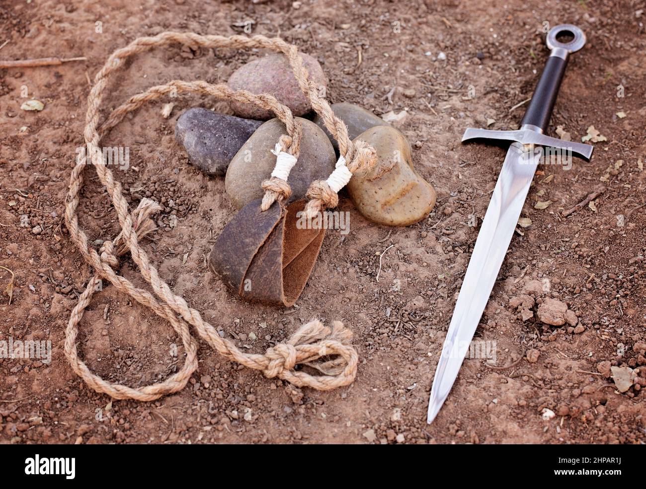 Fionda di Davide con cinque pietre lisce e Goliaths Sword nella sporcizia  Foto stock - Alamy