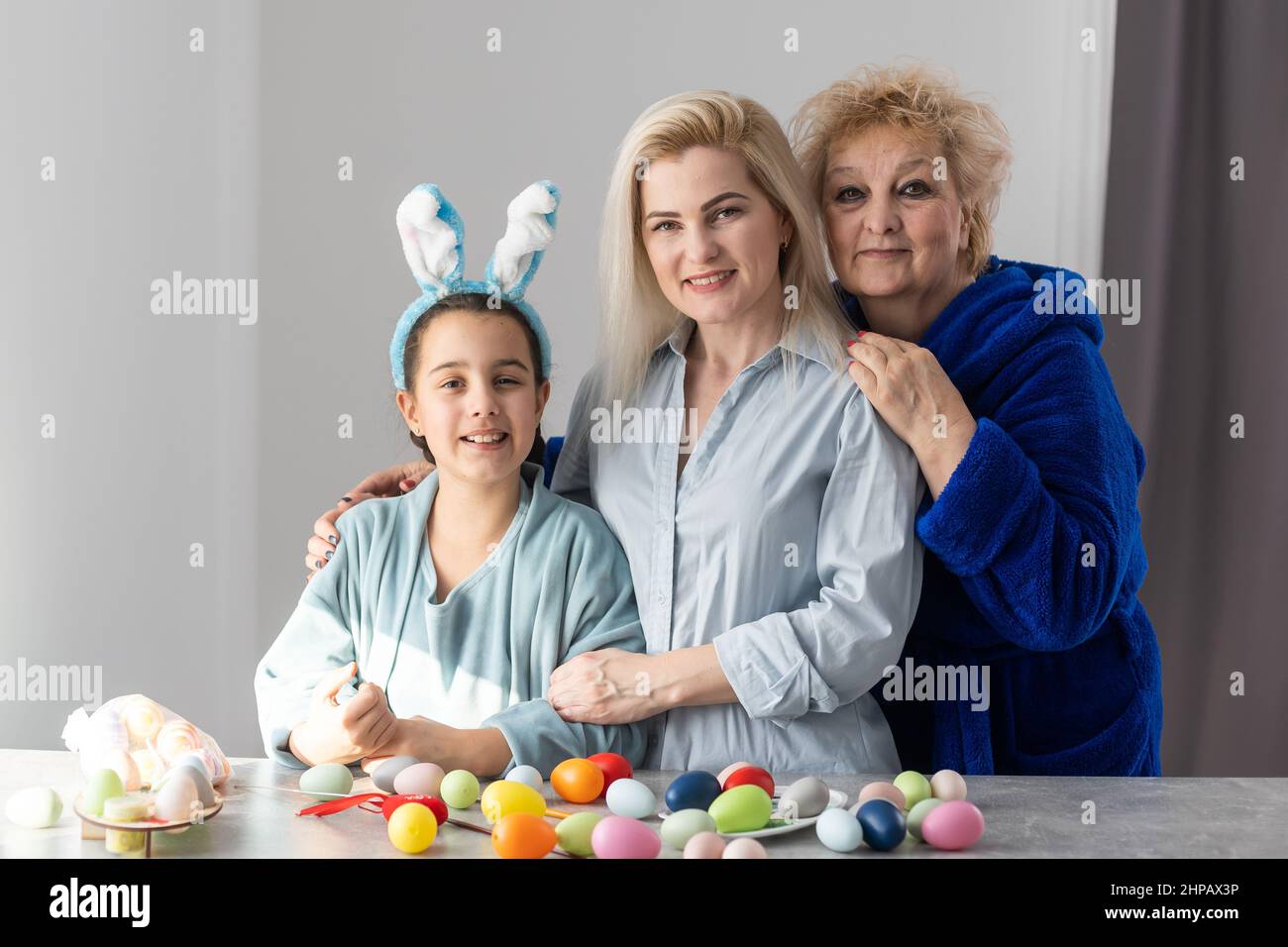 Sorridendo felice nonna caucasica, madre e figlia dipingere e decorare le uova di Pasqua avendo grande tempo insieme in cucina domestica Foto Stock
