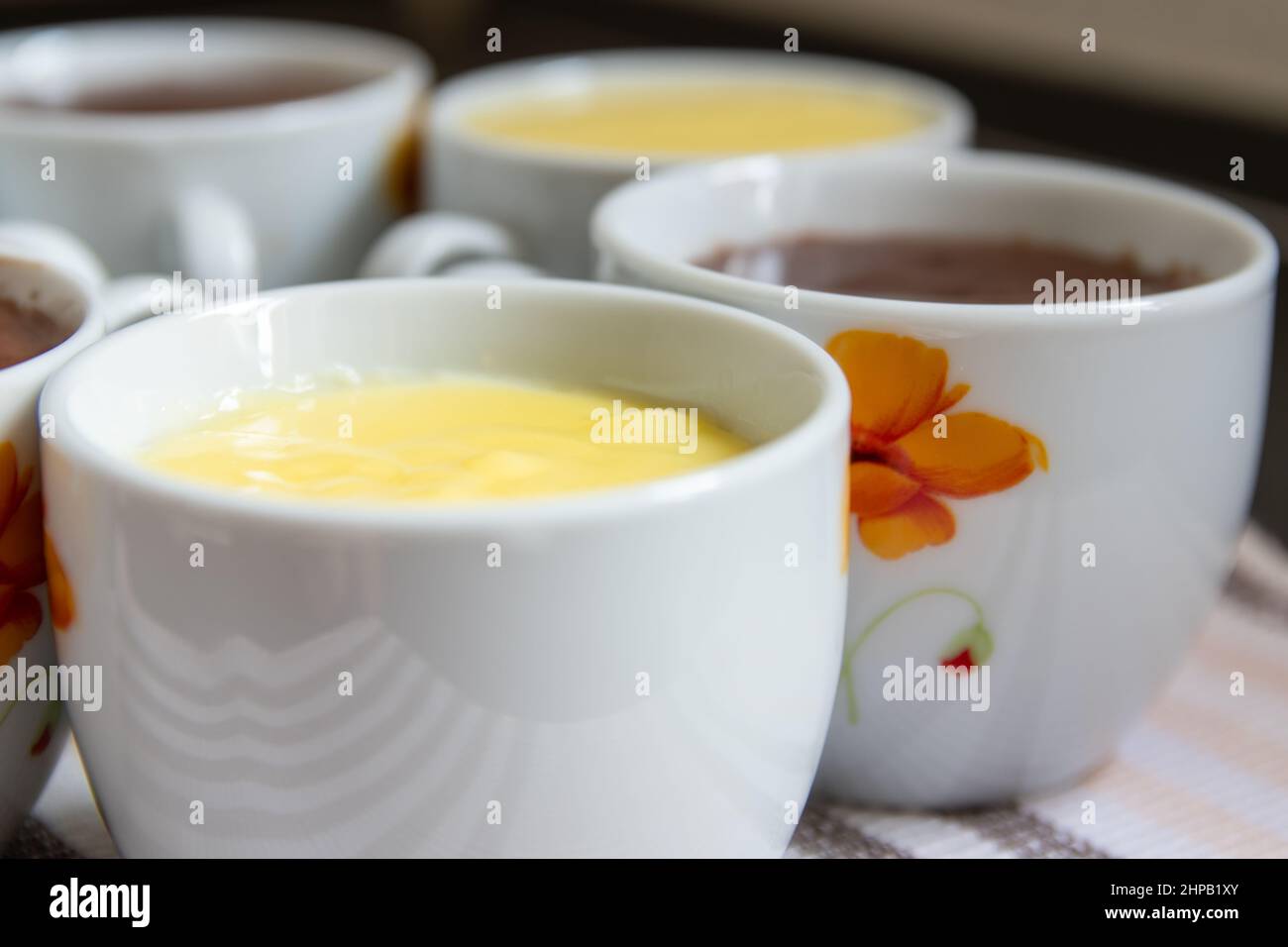 primo piano di bicchieri di porcellana riempiti di vaniglia gialla e di flummeria di cioccolato marrone Foto Stock