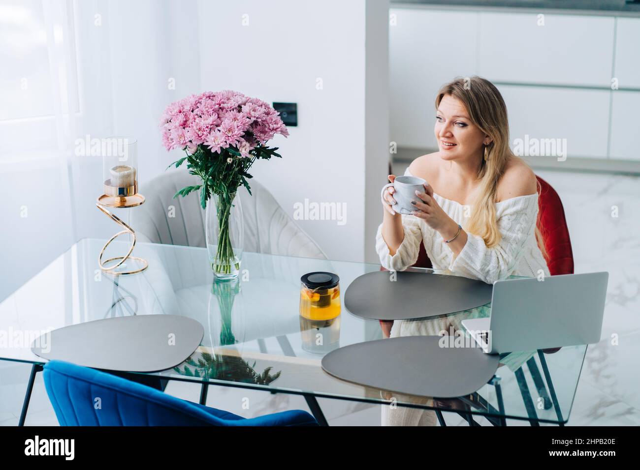 Bionda sorridente donna cucina agrumi tisana pentola. Videochiamata di lavoro in remoto Foto Stock