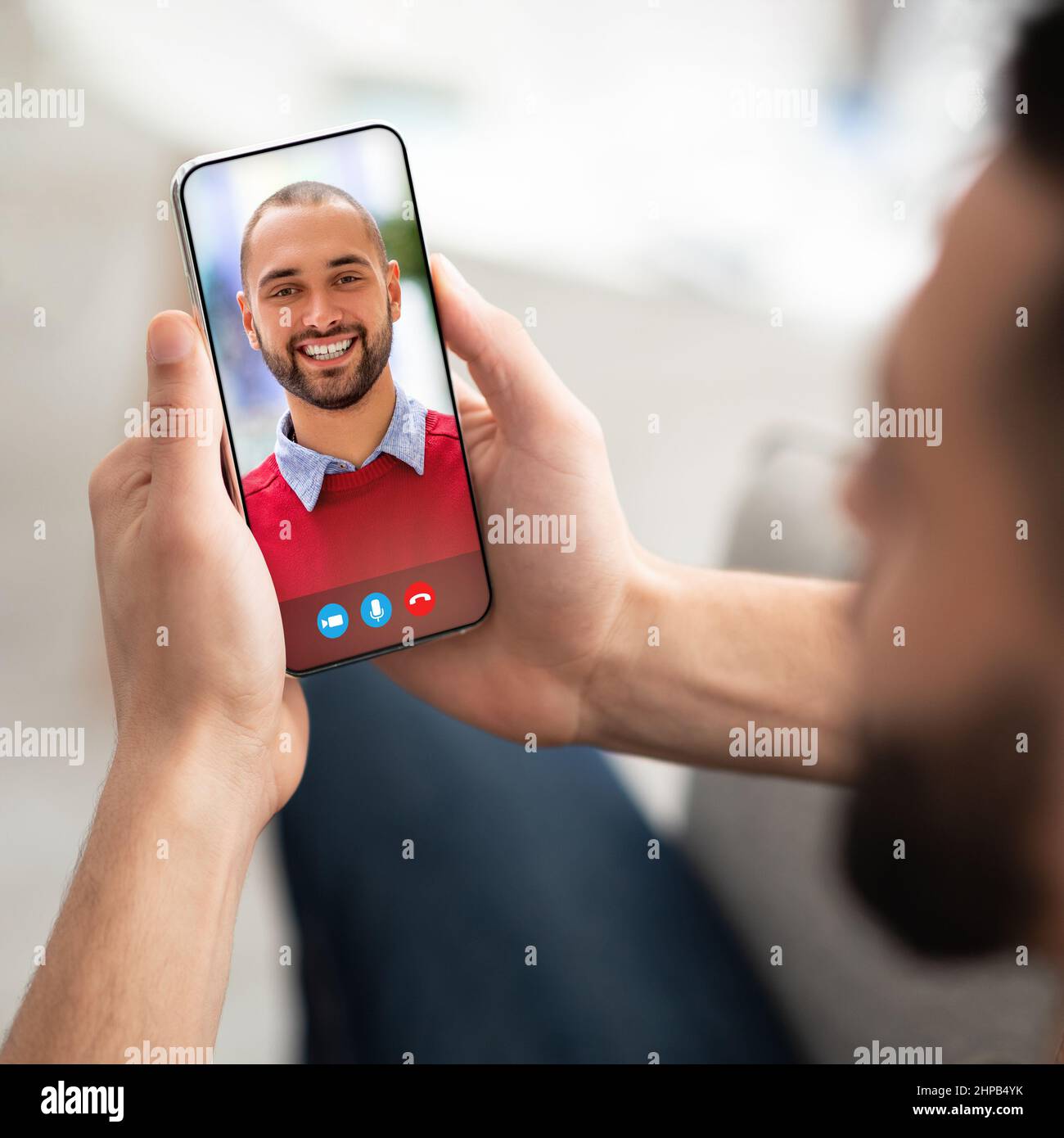 Giovane che usa lo smartphone per un incontro remoto con il suo amico arabo Foto Stock