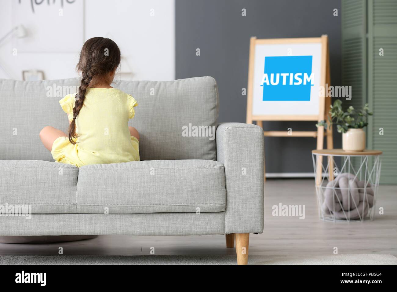 Piccola ragazza triste con disturbo autistico a casa, vista posteriore. Giornata mondiale di sensibilizzazione sull'autismo Foto Stock