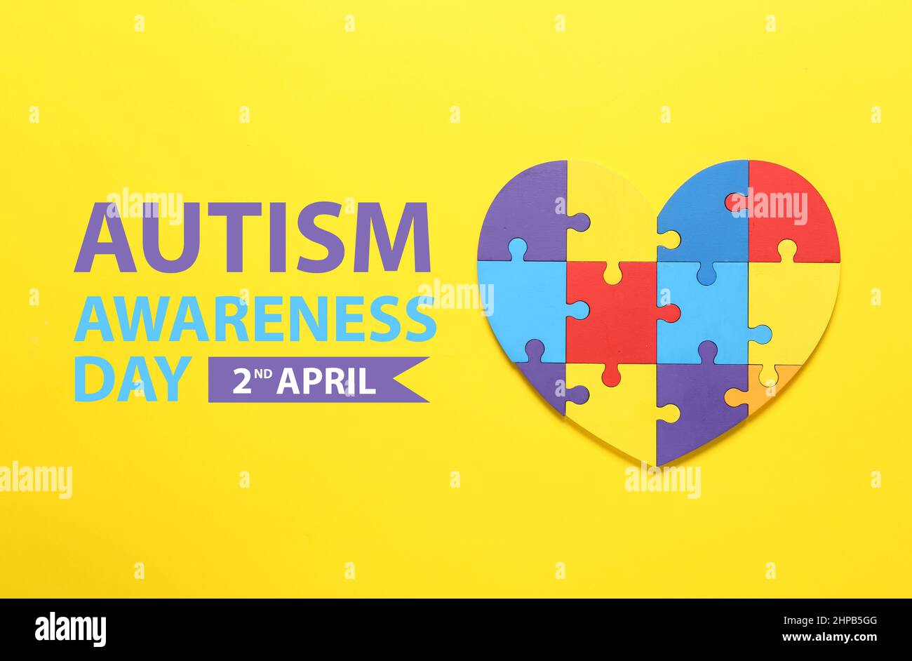 Pezzi di puzzle colorati a forma di cuore su sfondo giallo. Giornata mondiale di sensibilizzazione sull'autismo Foto Stock