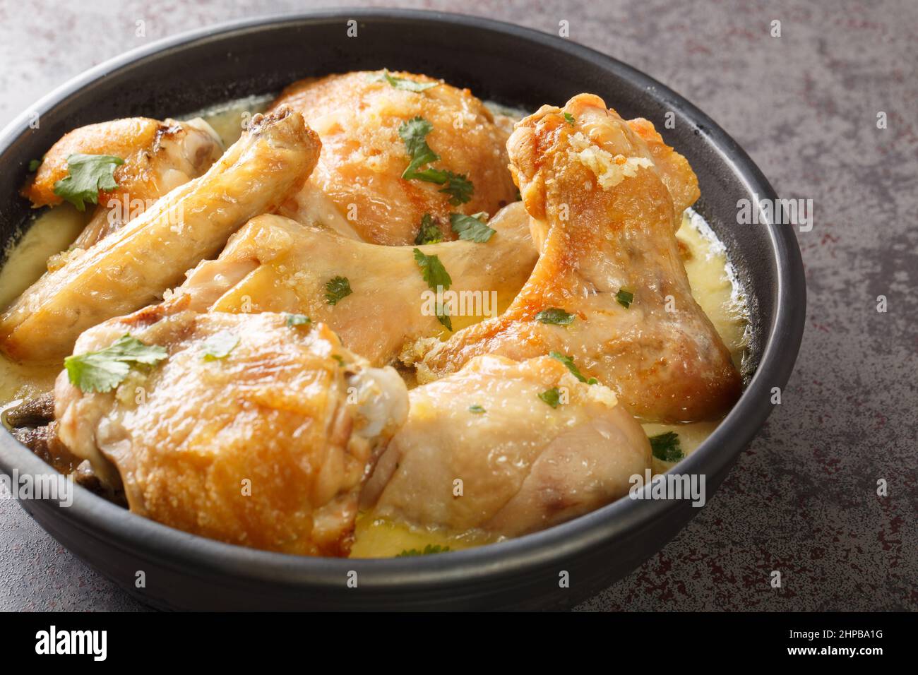 Shkmeruli è un piatto tradizionale caucasico georgiano di pollo in spicup salsa all'aglio nella pentola sul tavolo. Orizzontale Foto Stock