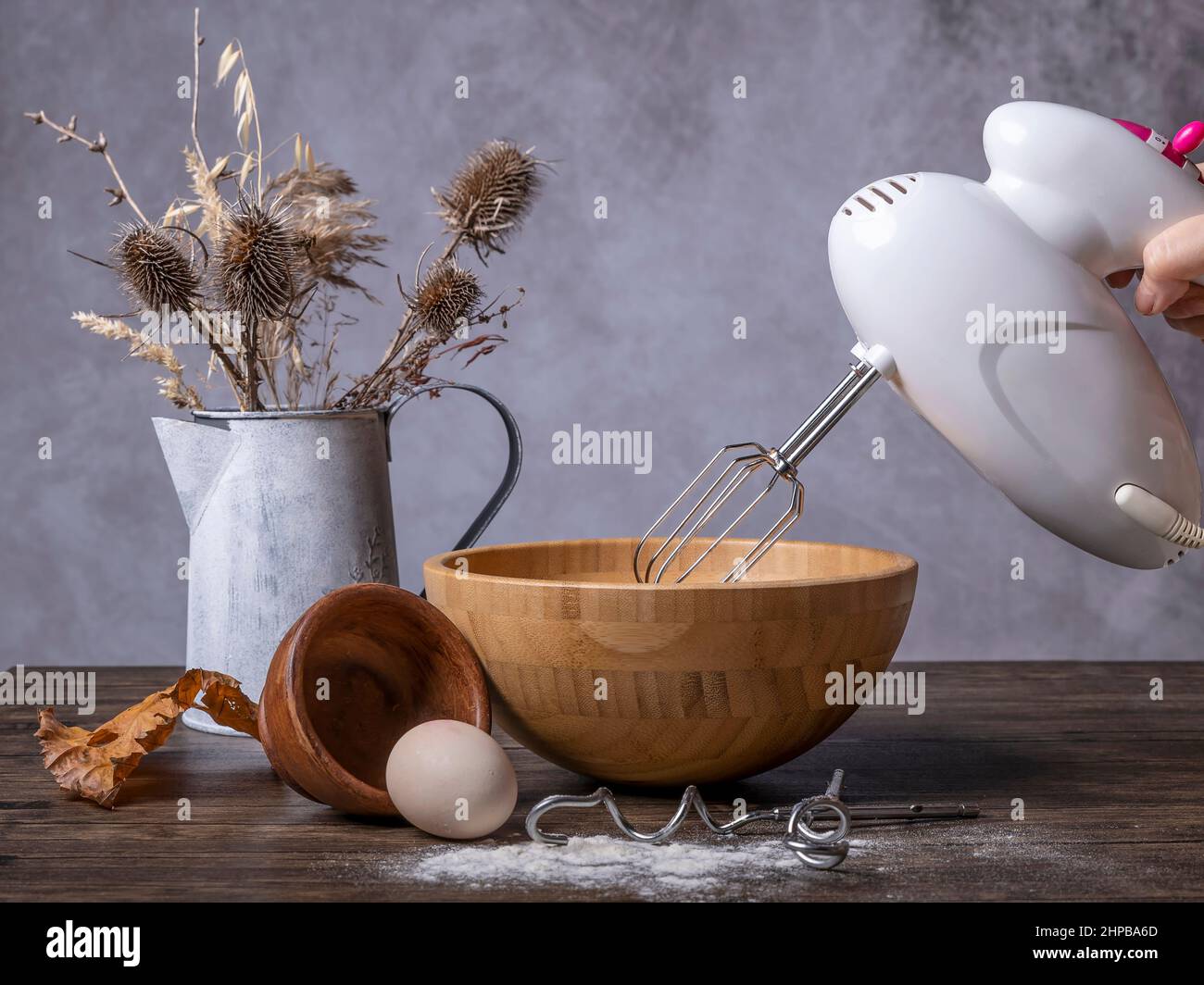 Una frusta elettrica da cucina viene utilizzata per preparare una torta a base di uova e farina mescolando gli ingredienti in un contenitore di legno Foto Stock