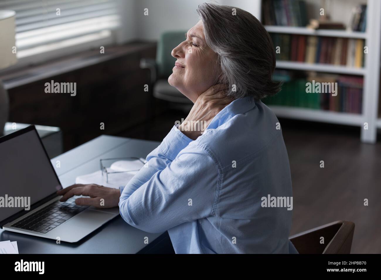 Stressata donna d'affari matura che soffre di collo rigido. Foto Stock