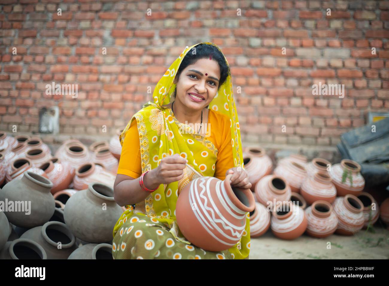 Ritratto di felice artista vasaio donna indiana pittura e decorazione disegno su vaso di argilla in vendita, artigianato, abilità india. Foto Stock