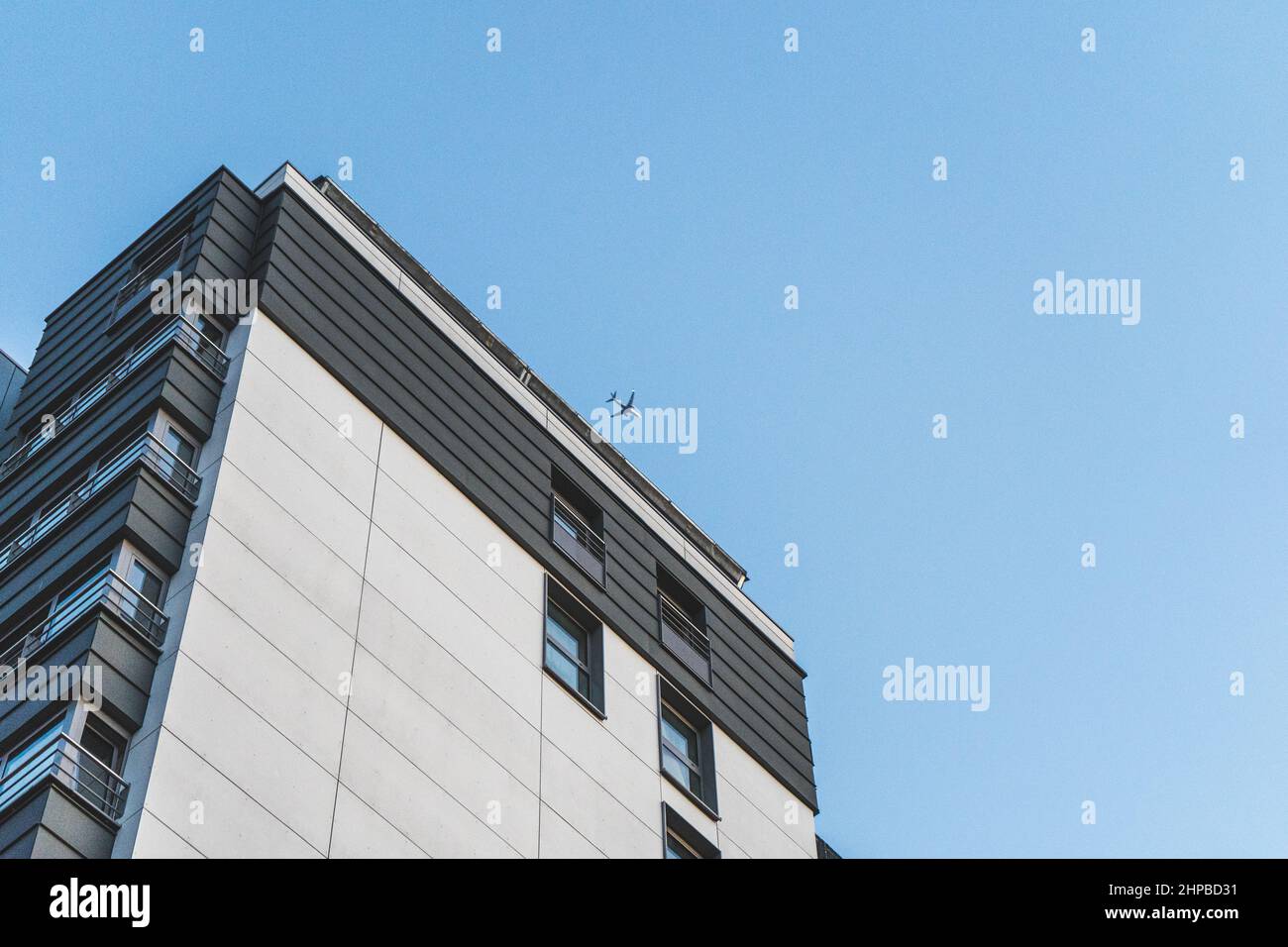 Edificio alto a Bruxelles, Belgio. L'aeroplano vola nel cielo blu senza nuvole sopra Foto Stock