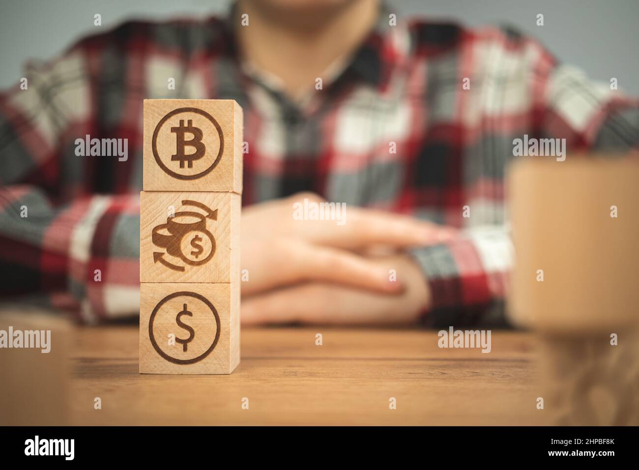 Bitcoin scambiano i simboli del dollaro su un cubetto di legno nelle mani. Concetto di criptovaluta e fondo in contanti, tavolo in legno Foto Stock