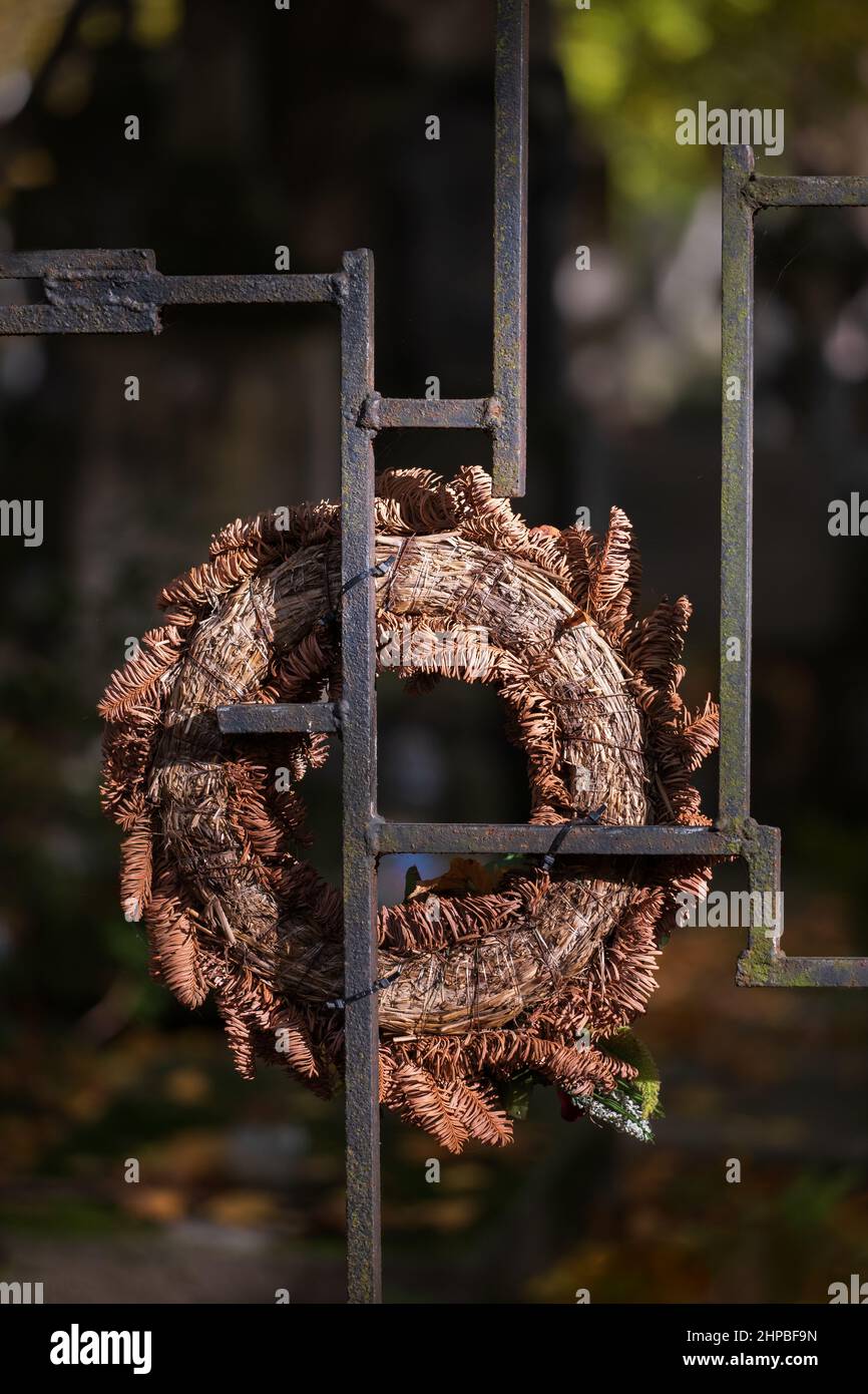 Vecchio asciugò su wreath su vecchi barrette di recinzione di metallo nel cimitero. Foto Stock