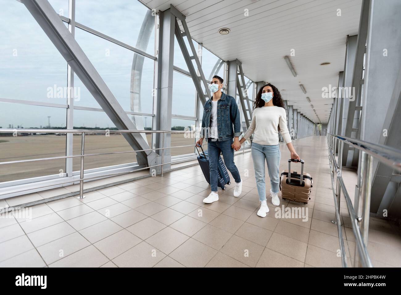 Assistenza sanitaria e viaggi. Coppia mediorientale in maschere mediche a piedi all'aeroporto Foto Stock