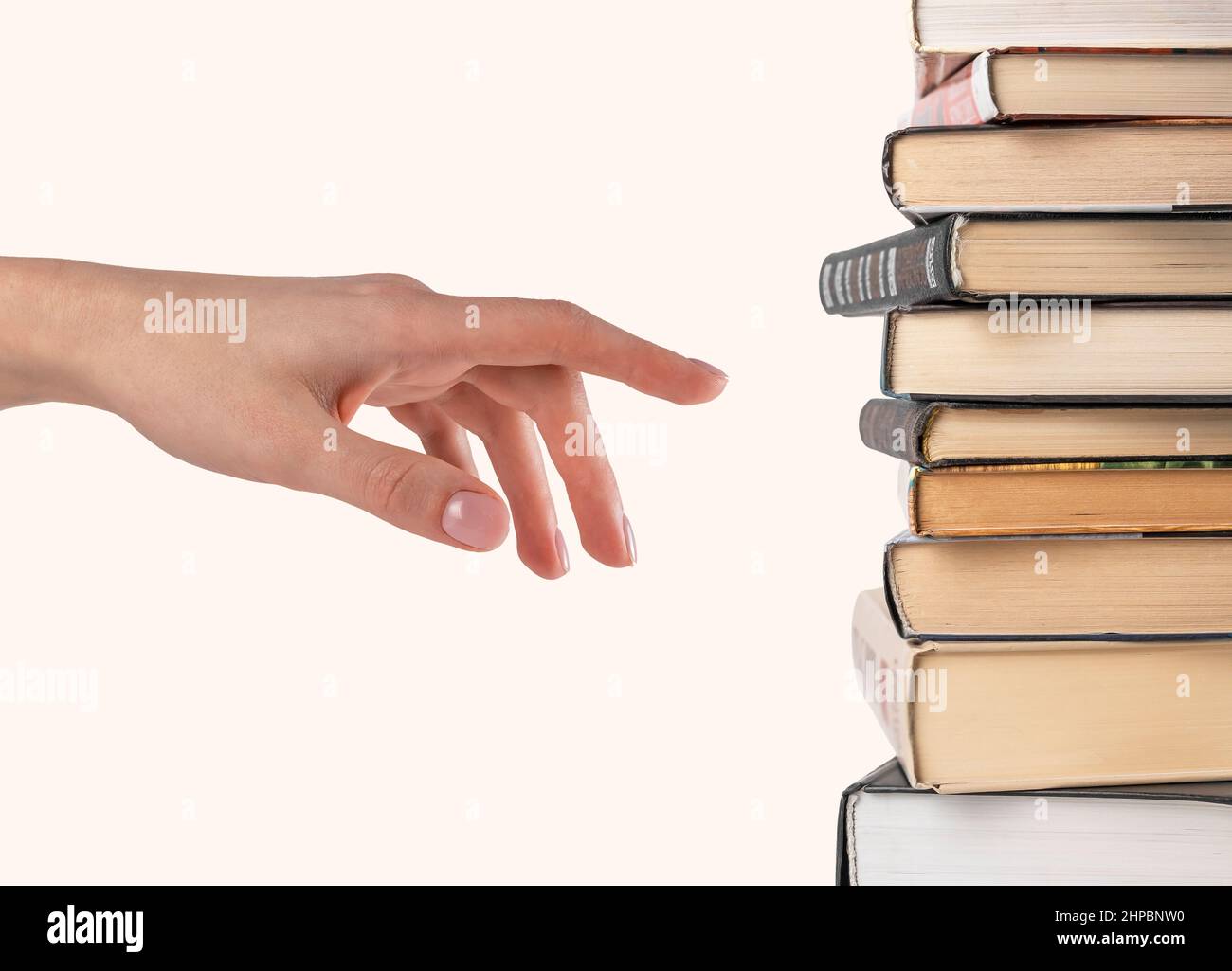 Donna mano che seleziona o punta a libro da stack isolato su sfondo bianco. Scelta del libro per la lettura. Foto di alta qualità Foto Stock