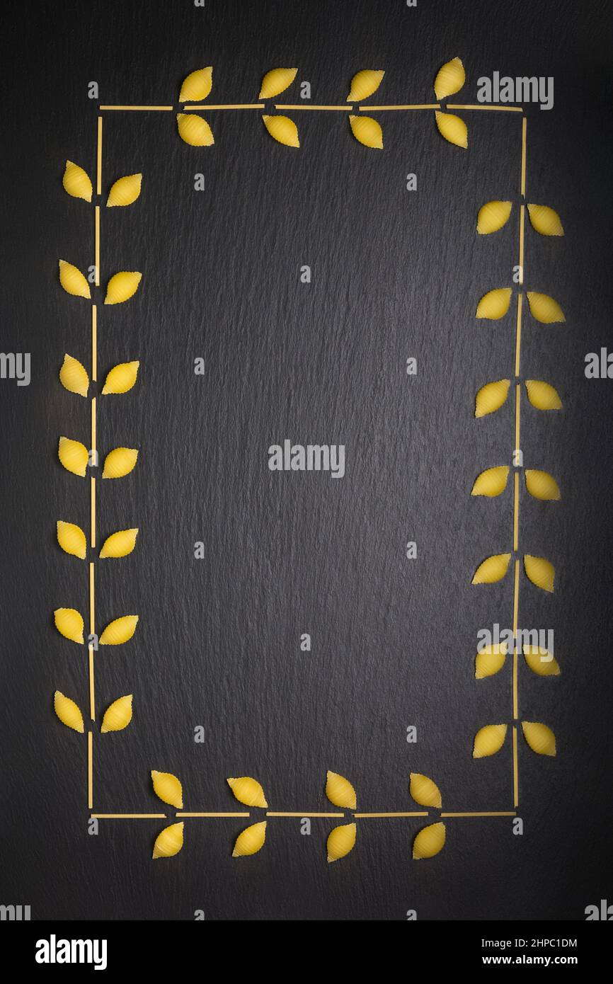 varietà di pasta cruda disposta come cornice, isolata su sfondo nero ardesia, dieta e concetto di cibo, vista dall'alto con spazio copia Foto Stock