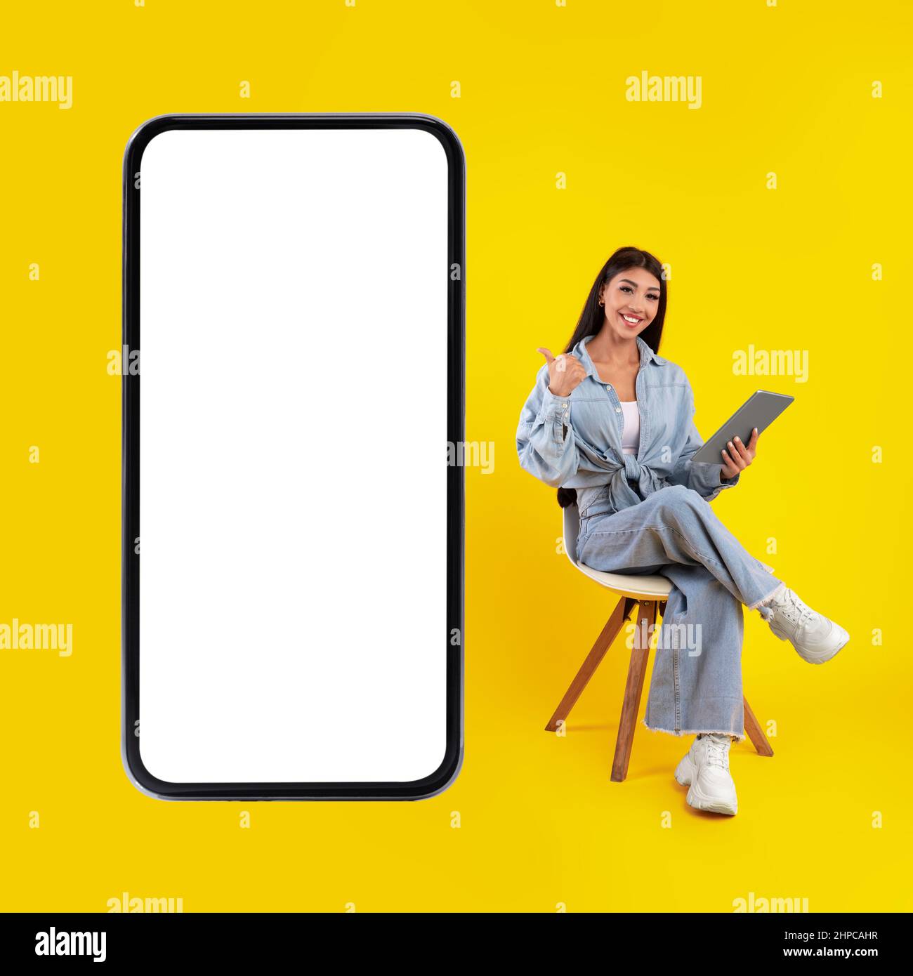 Signora felice usando il tablet che punta allo schermo del telefono cellulare Foto Stock