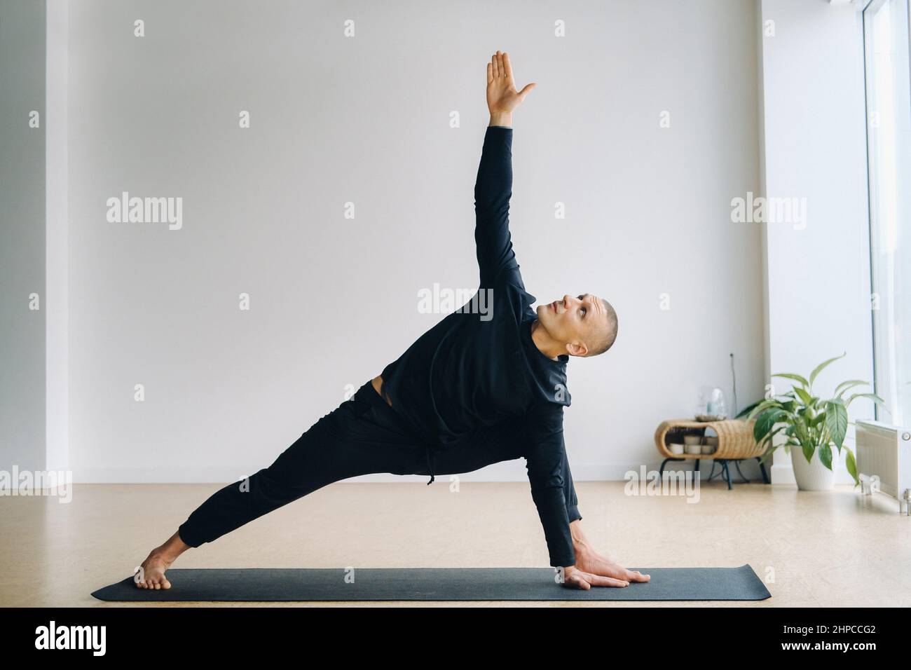 Un uomo di abbigliamento sportivo nero sta facendo yoga, stretching in palestra Foto Stock