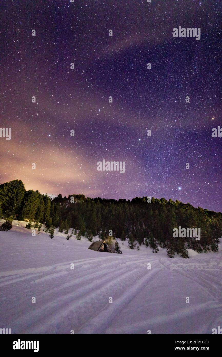 Piccolo rifugio di montagna nella neve in una notte di vino stellato Foto Stock