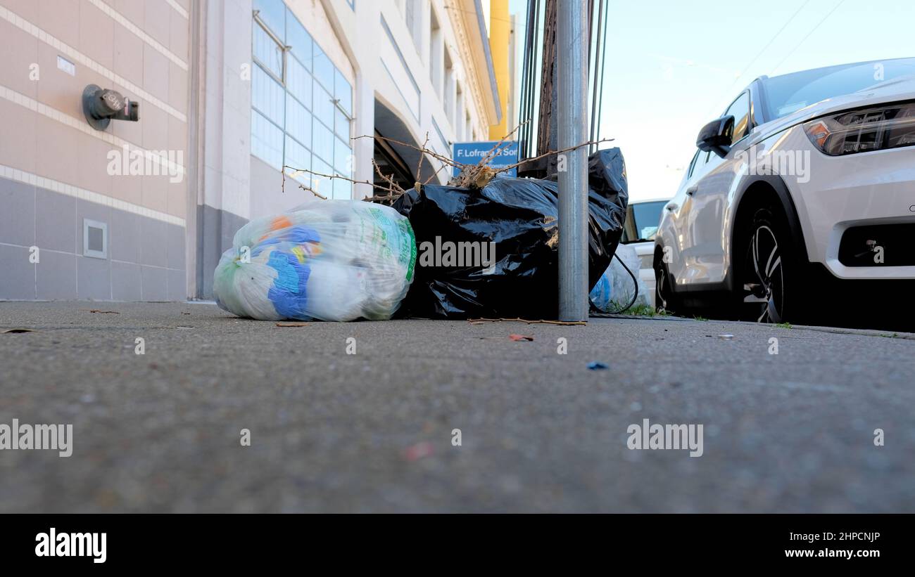 Sacchetti di plastica trasparenti e neri per rifiuti su un marciapiede a San Francisco, California; sporcizia urbana, rifiuti, detriti, spazzatura, e lettiera; responsabilità civica Foto Stock