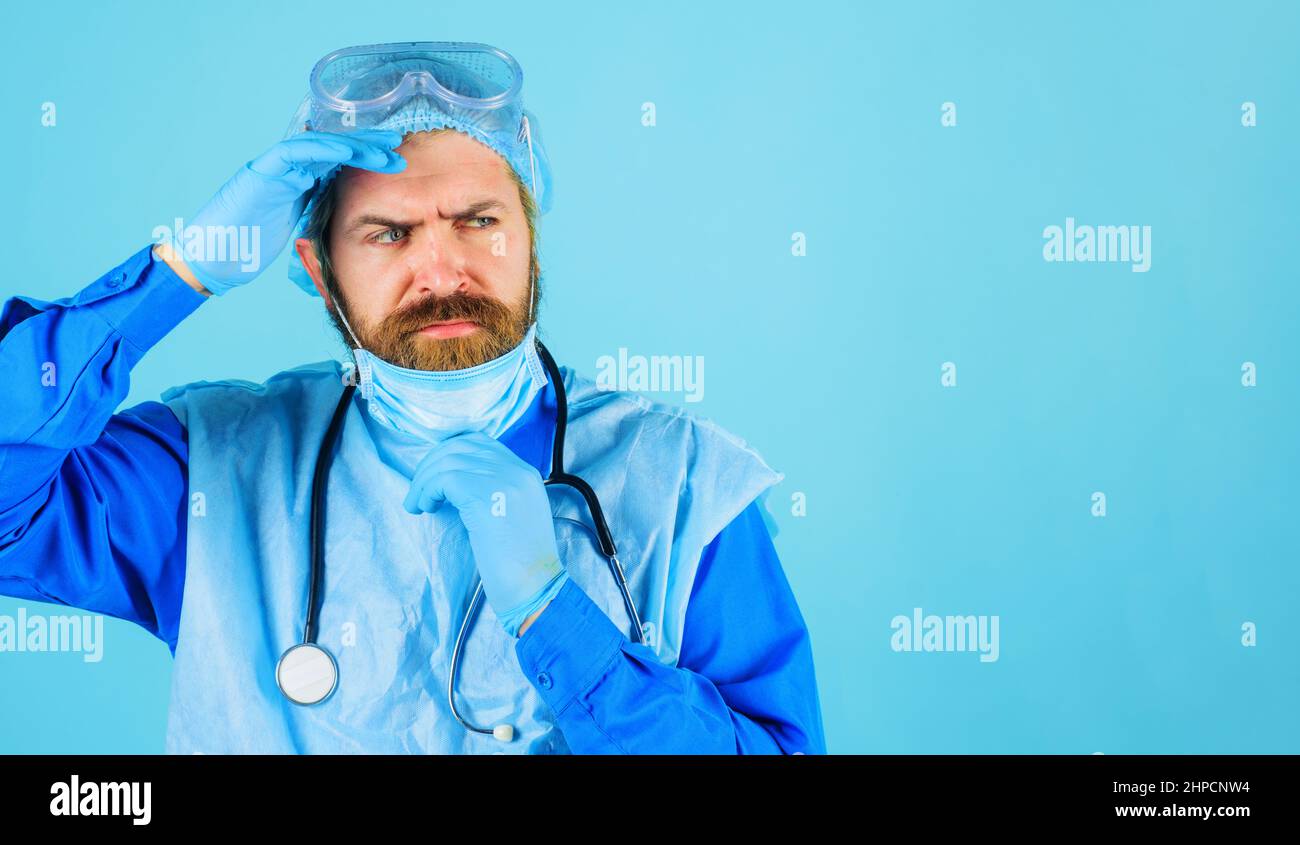 Medico in cappuccio medico, maschera e occhiali protettivi con stetoscopio. Operaio ospedaliero. Foto Stock