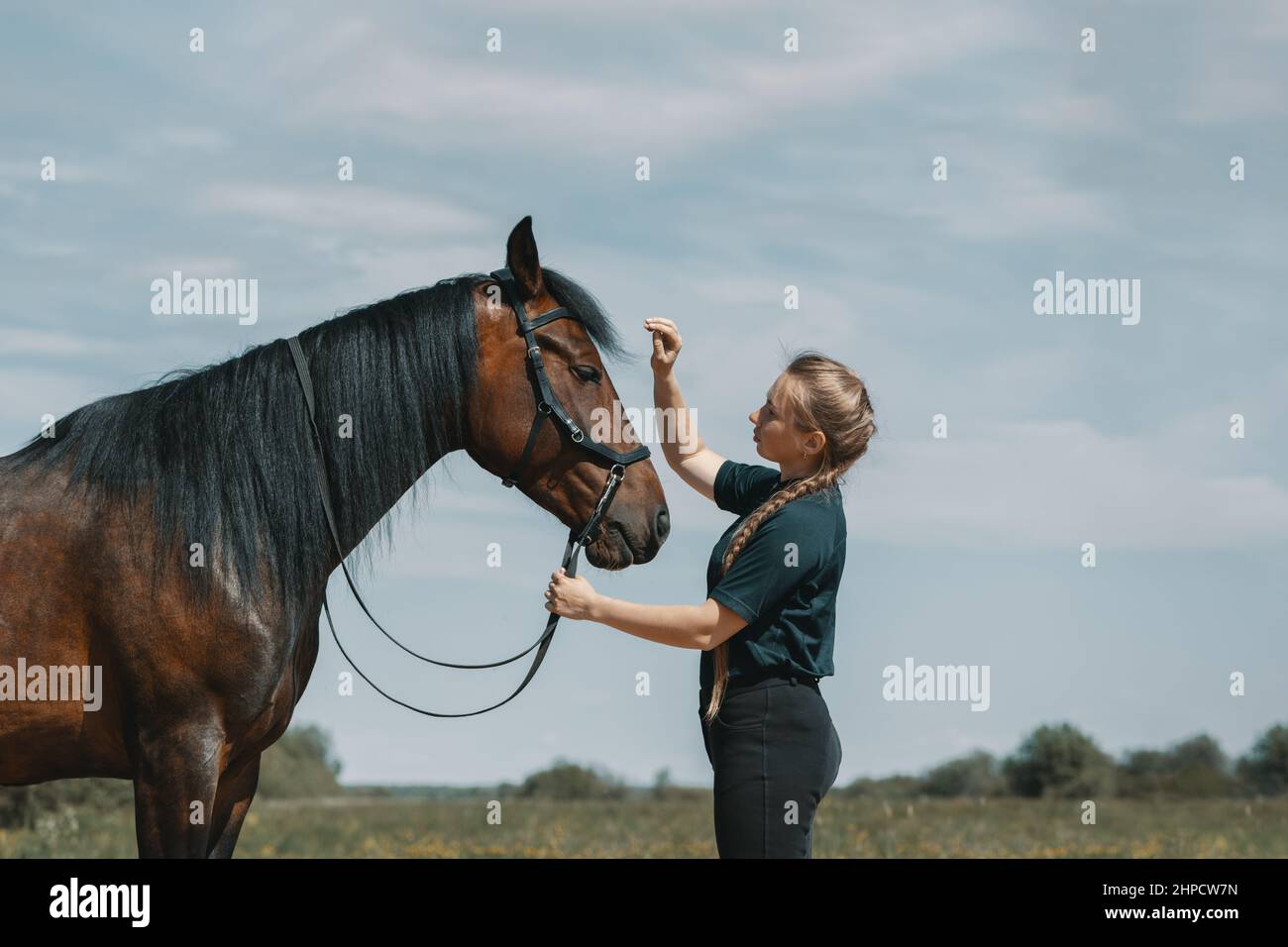 Donna caucasica che tiene le redini di cavallo con la mano all'aperto. Foto Stock