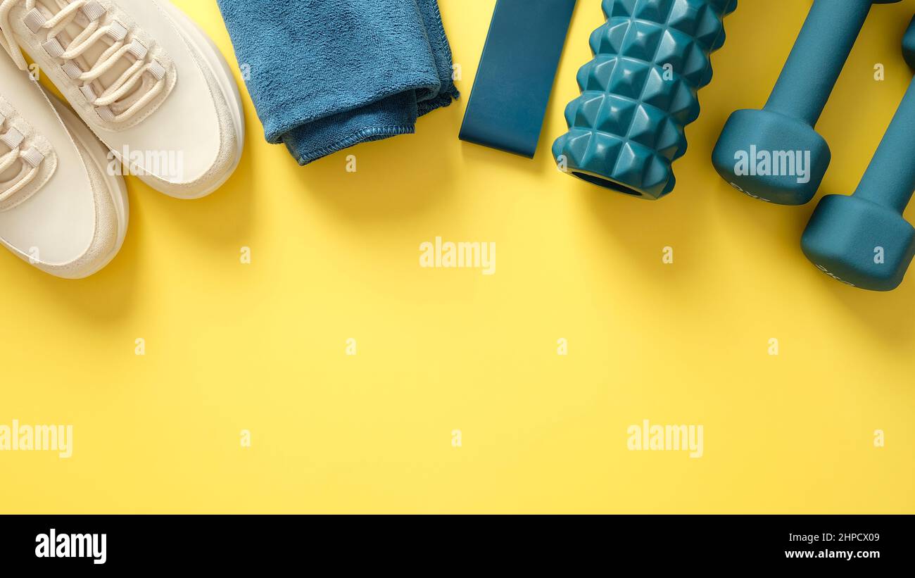 Vista dall'alto degli accessori per il fitness. Attrezzature sportive e da palestra isolate su sfondo giallo Foto Stock