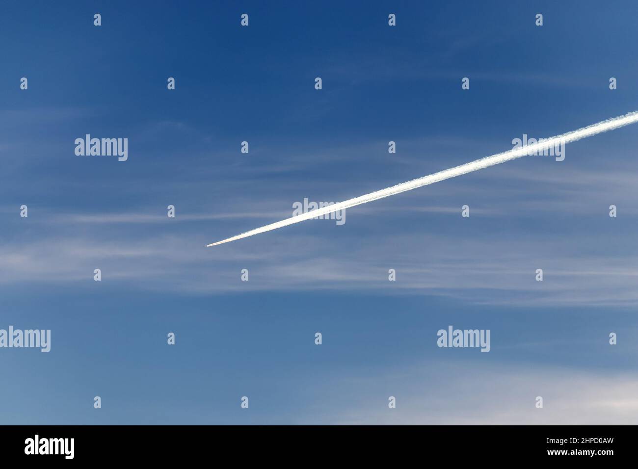 Contrails - un aereo di trasporto volante con piste bianche di condensazione nel cielo blu Foto Stock