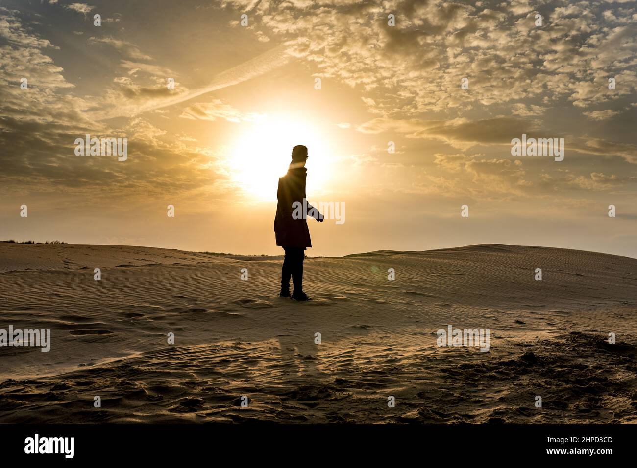 Silhouette di un uomo sulle dune al tramonto. Deserto e sabbia. Foto Stock