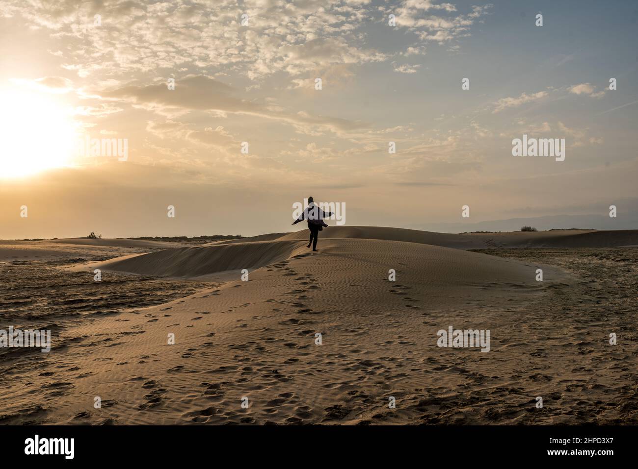Donna che cammina lungo le dune di sabbia al tramonto. Libertà Foto Stock