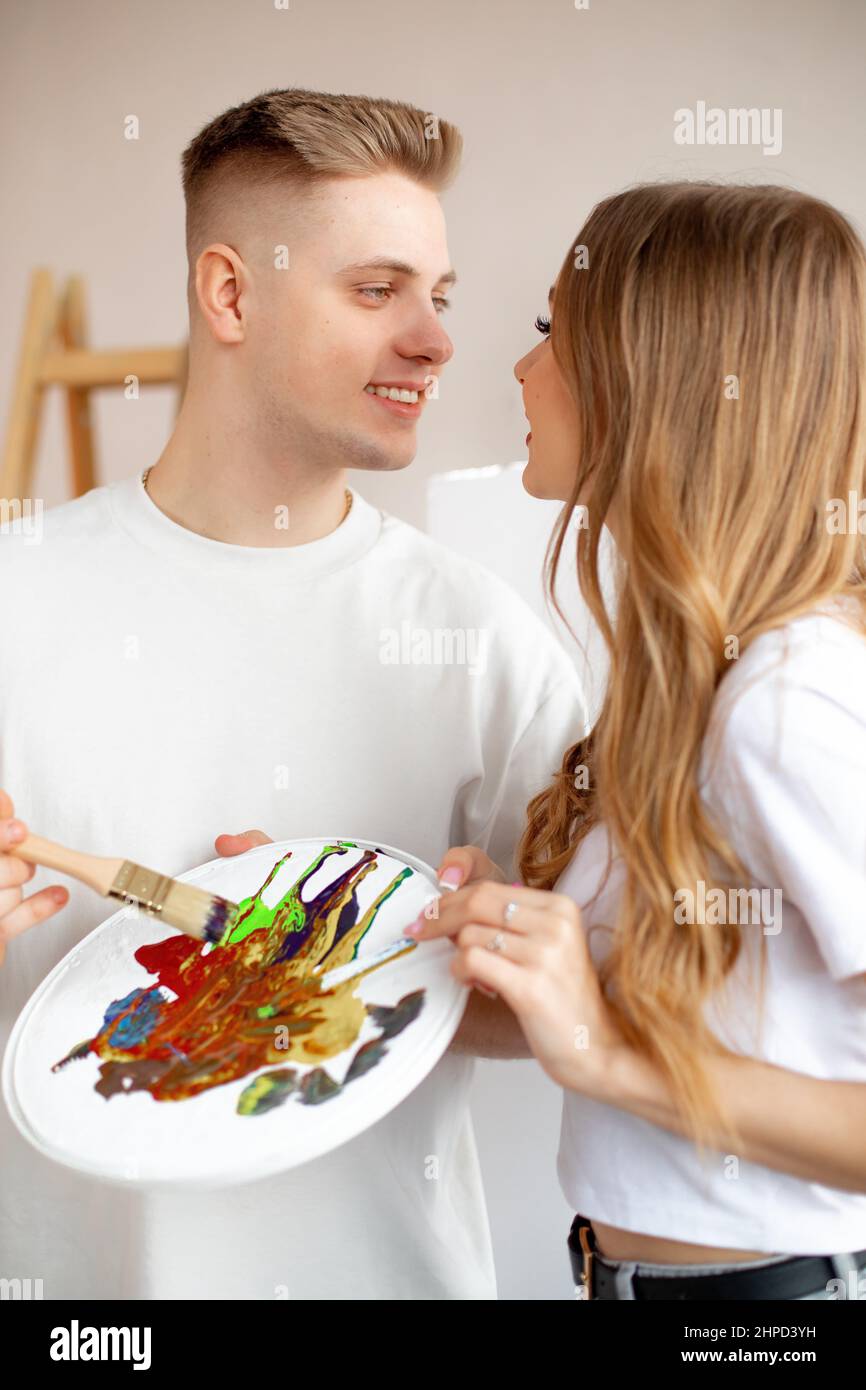 Ritratto di felice sorridente giovane coppia attraente con capelli fiera stand incontro occhi, tenendo acquerello tavolozza, spazzola. Foto Stock