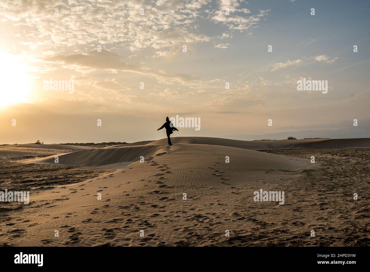 Donna che cammina lungo le dune di sabbia al tramonto. Libertà Foto Stock