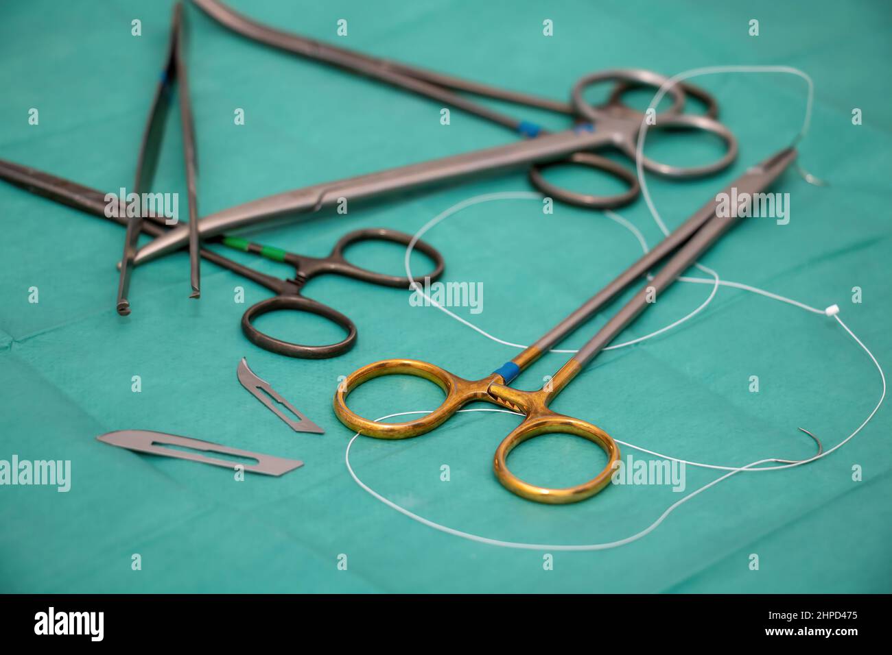 Strumento chirurgico sterilizzato su fondo tessuto verde. Medico chirurgo utensile in acciaio inox, pinzette, porta-aghi o cacciavite, forbici, lama, sutu Foto Stock