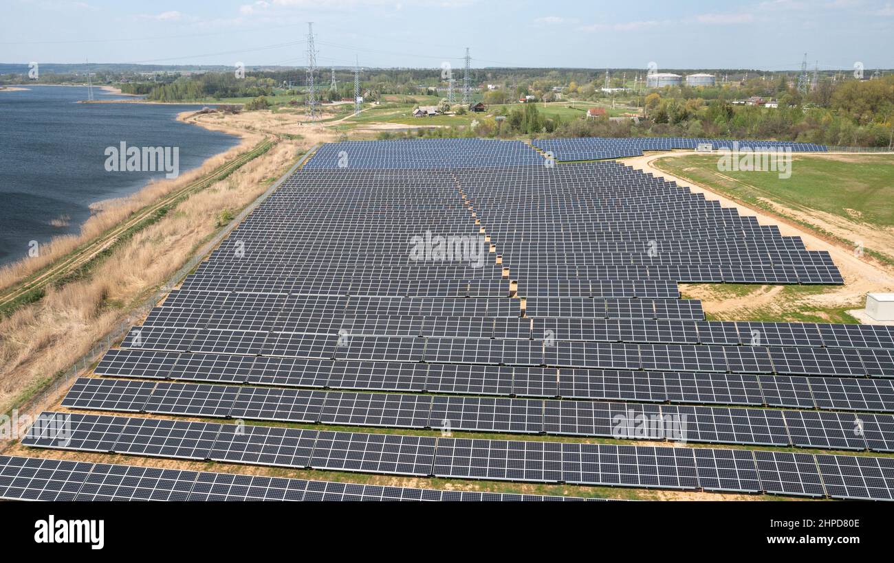 Campo con array di pannelli solari che generano energia elettrica rinnovabile Foto Stock