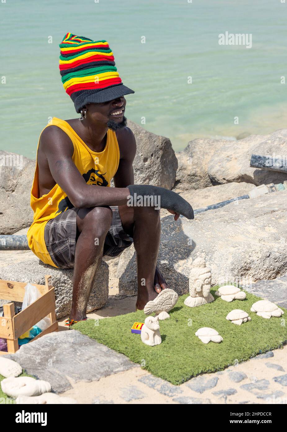Uomo che vende figure di sabbia intagliata sul pontao Santa Maria pescatore molo, Praia Santa Maria, Santa Maria, SAL, República de Cabo (Capo Verde) Foto Stock