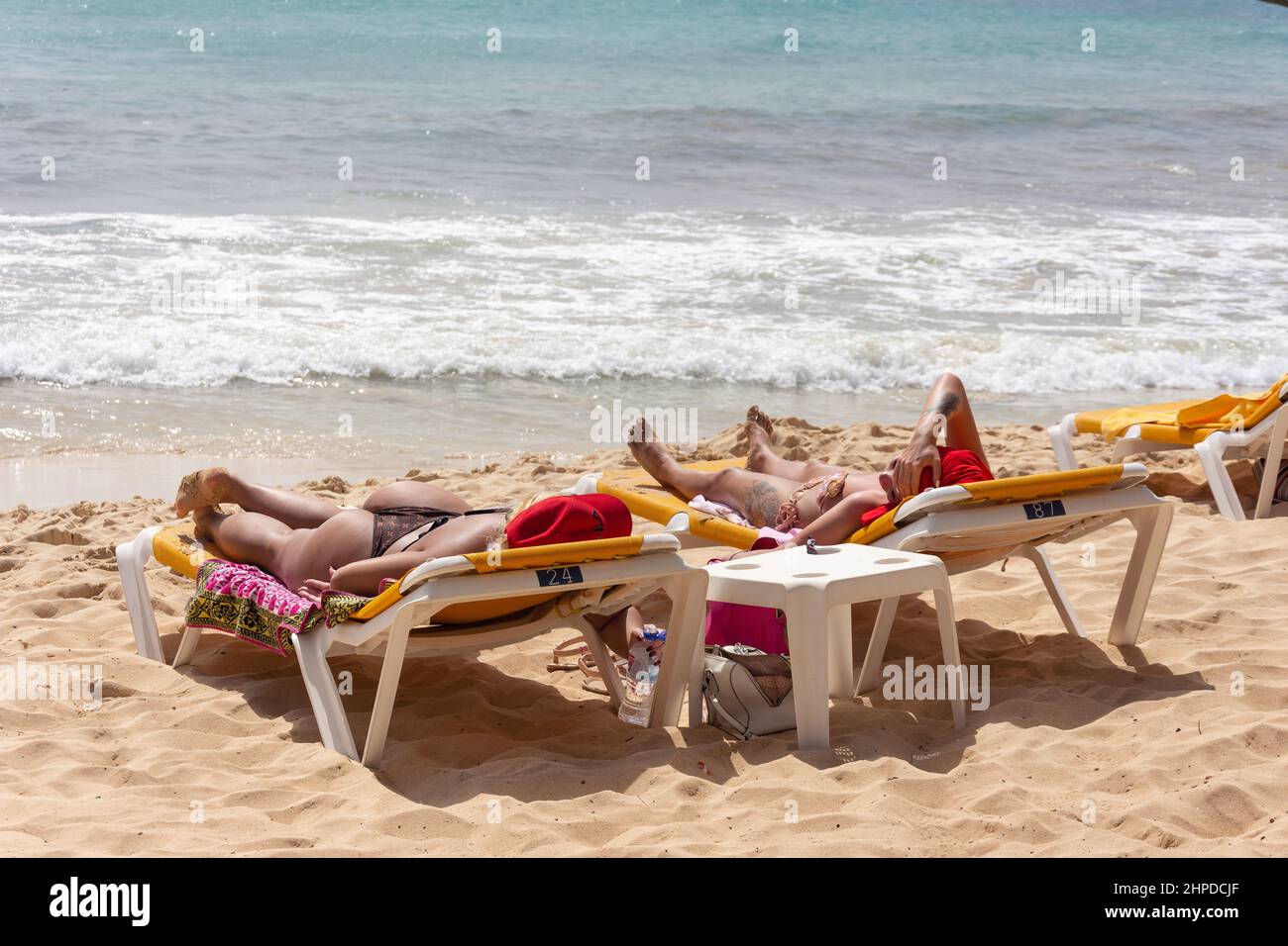 Giovani donne che prendono il sole sui lettini, Praia Santa Maria, Santa Maria, SAL, República de Cabo (Capo Verde) Foto Stock