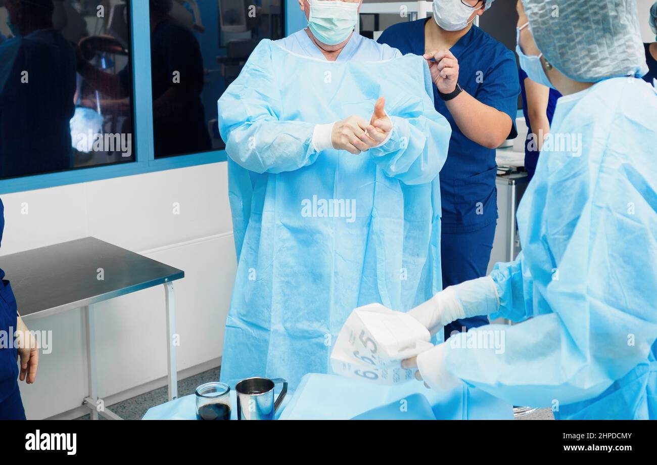I chirurghi si vestono in uniformi blu sterili prima dell'intervento chirurgico. Messa a fuoco selettiva. Foto Stock