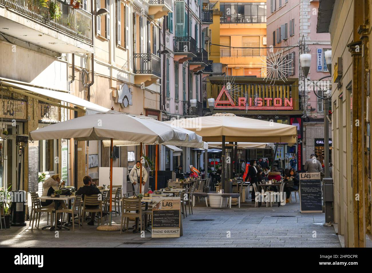 Vista sulla strada del centro città con caffè sul marciapiede e il Teatro Ariston, sede del Festival Italiano delle canzoni, Sanremo, Imperia, Liguria, Italia Foto Stock