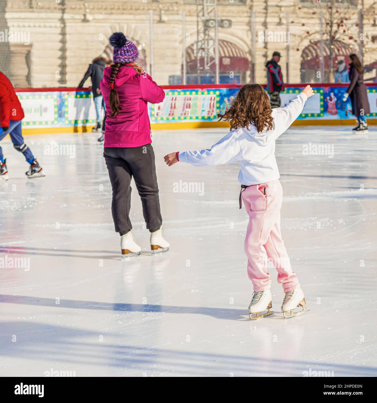 Felice ragazza pattinaggio su ghiaccio sulla pista di pattinaggio nel parco della città. Sano inverno attività all'aperto Foto Stock