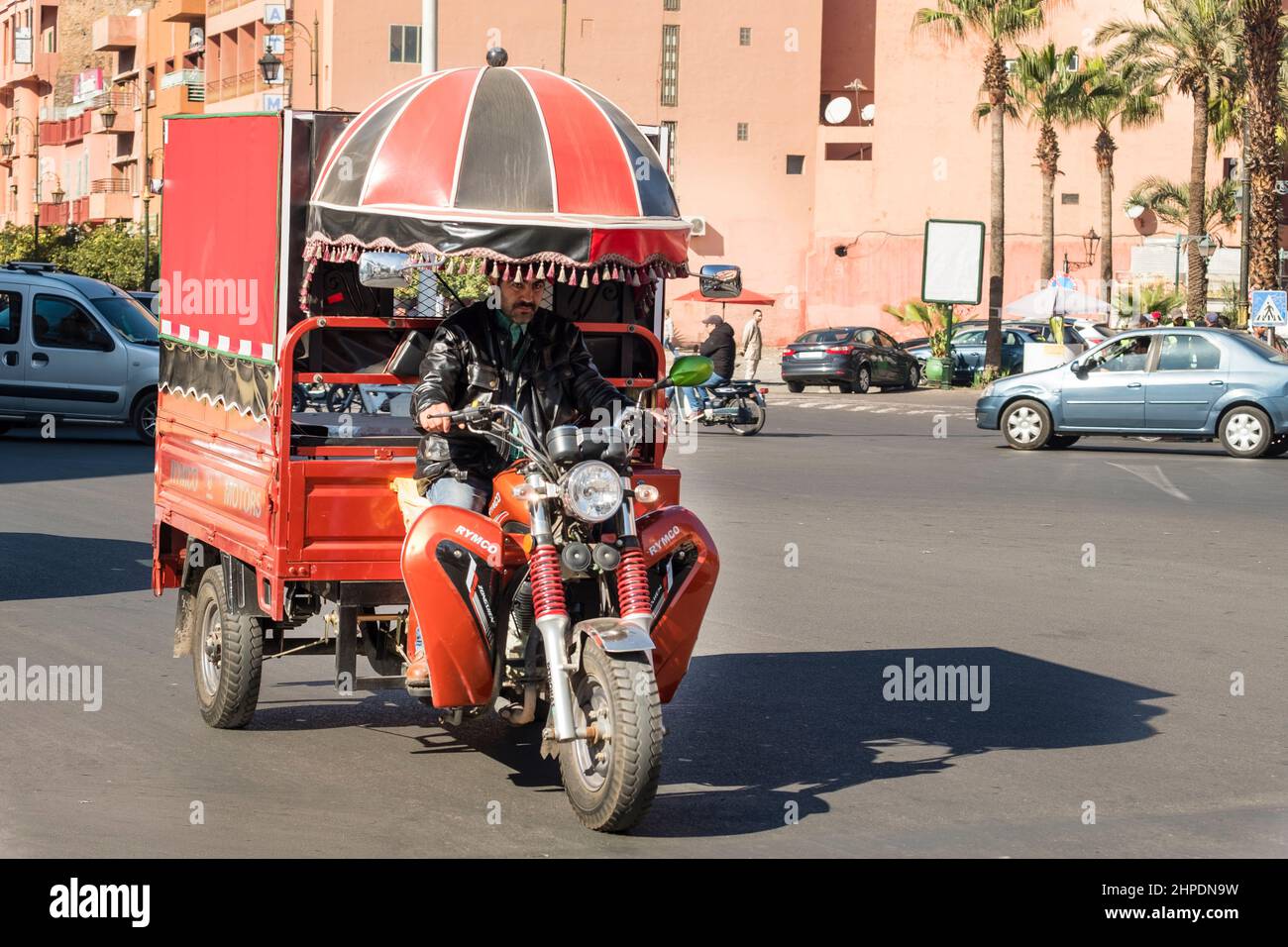 L'uomo marocchino guida la sua colorata moto con il carro per le strade di Marrakech Foto Stock