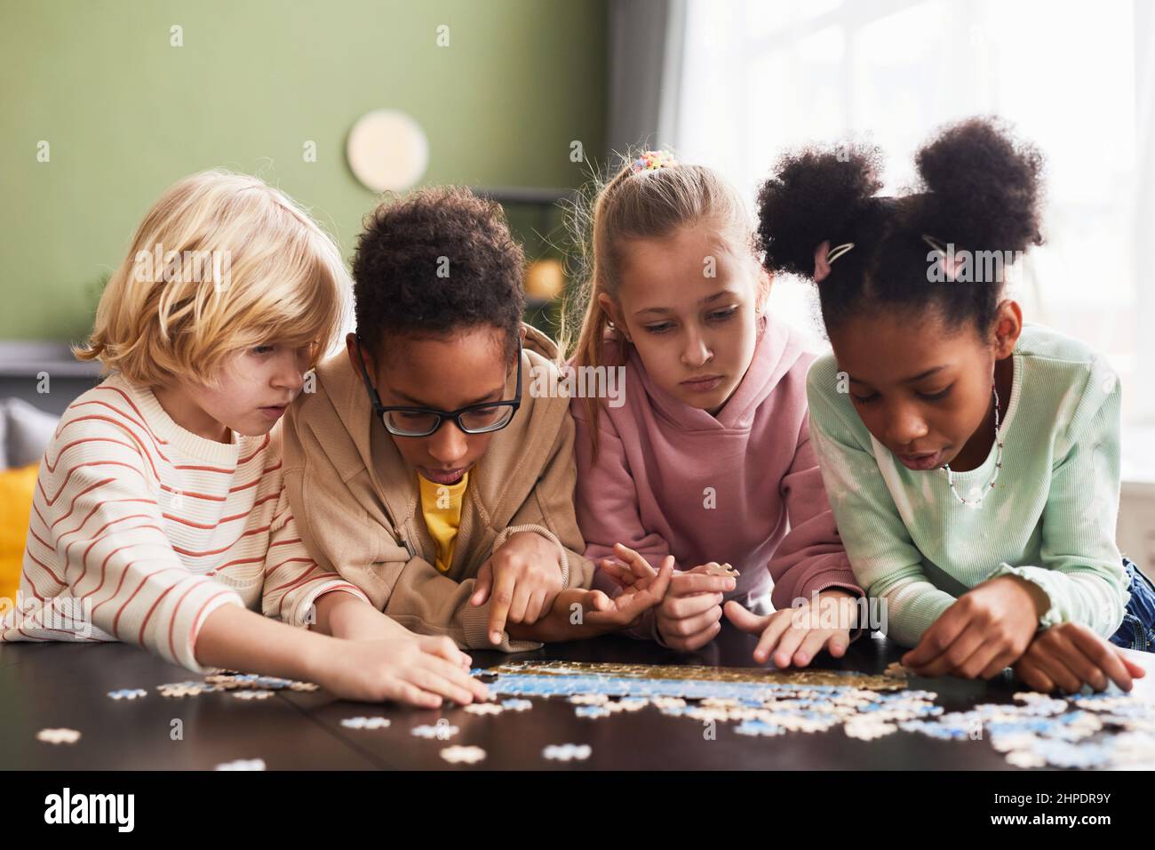 Ritratto della vista frontale di diversi gruppi di bambini che giocano con gioco di puzzle in interni insieme Foto Stock