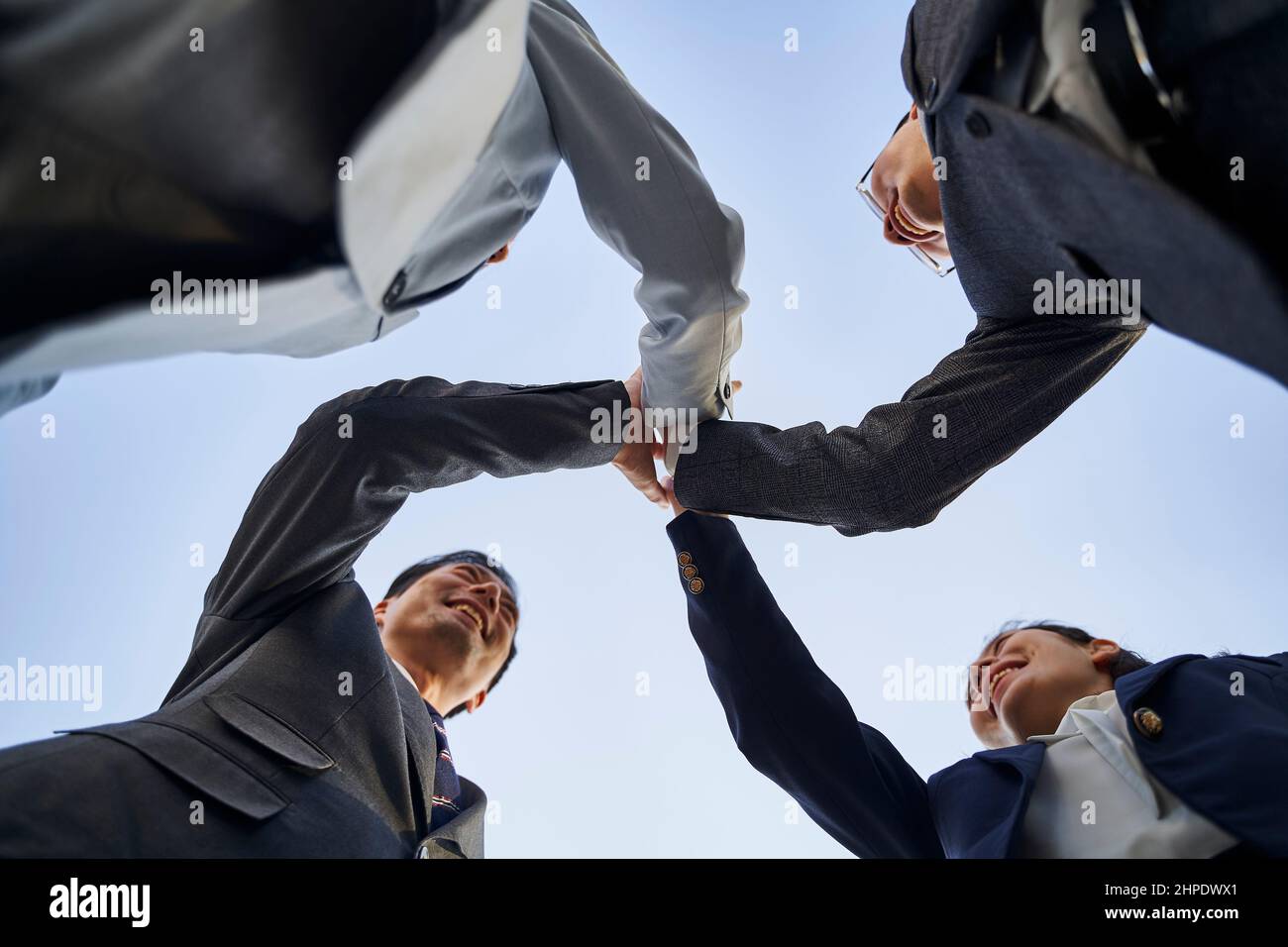 gruppo di uomini e donne d'affari asiatici che mettono le mani a toghter per mostrare lo spirito di squadra e l'unità Foto Stock