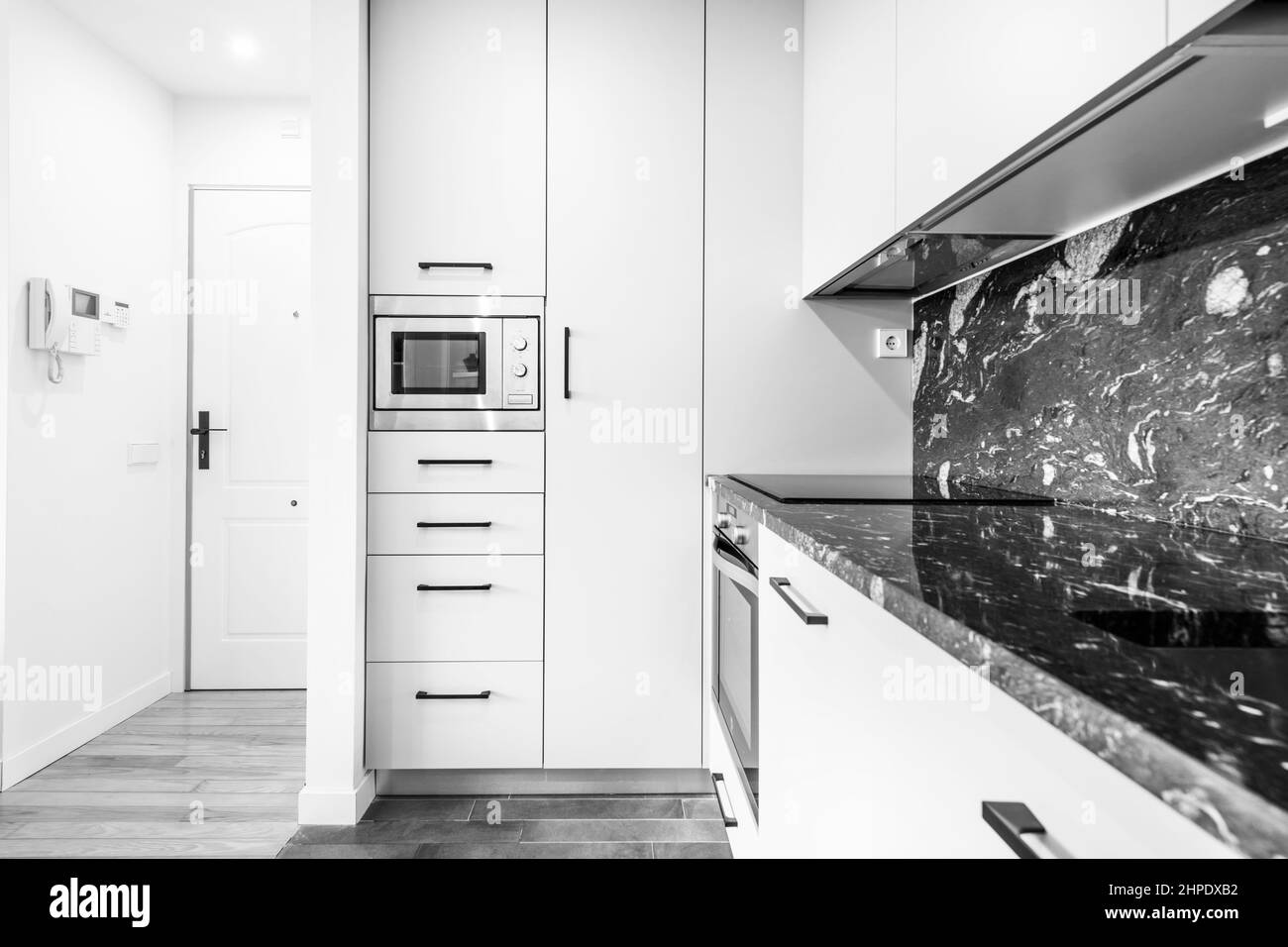 Appartamento cucina con piano in marmo nero e parete con lunghi armadi e cassetti Foto Stock