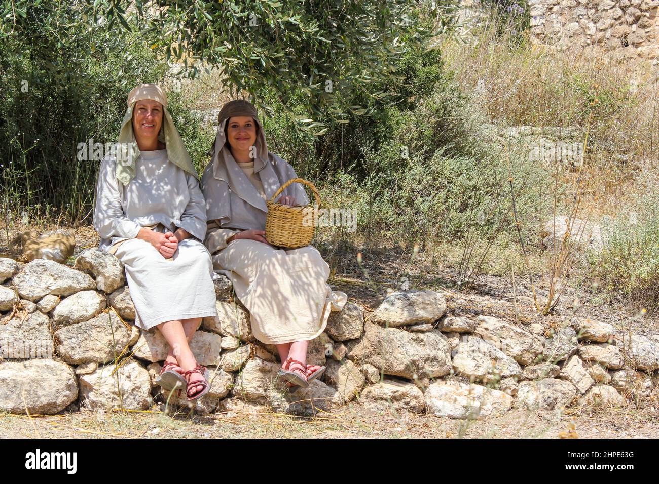 Le Attrici raffiguranti le donne del primo secolo si siedono all'ombra del museo all'aperto del villaggio di Nazareth a Nazareth, Israele. Foto Stock