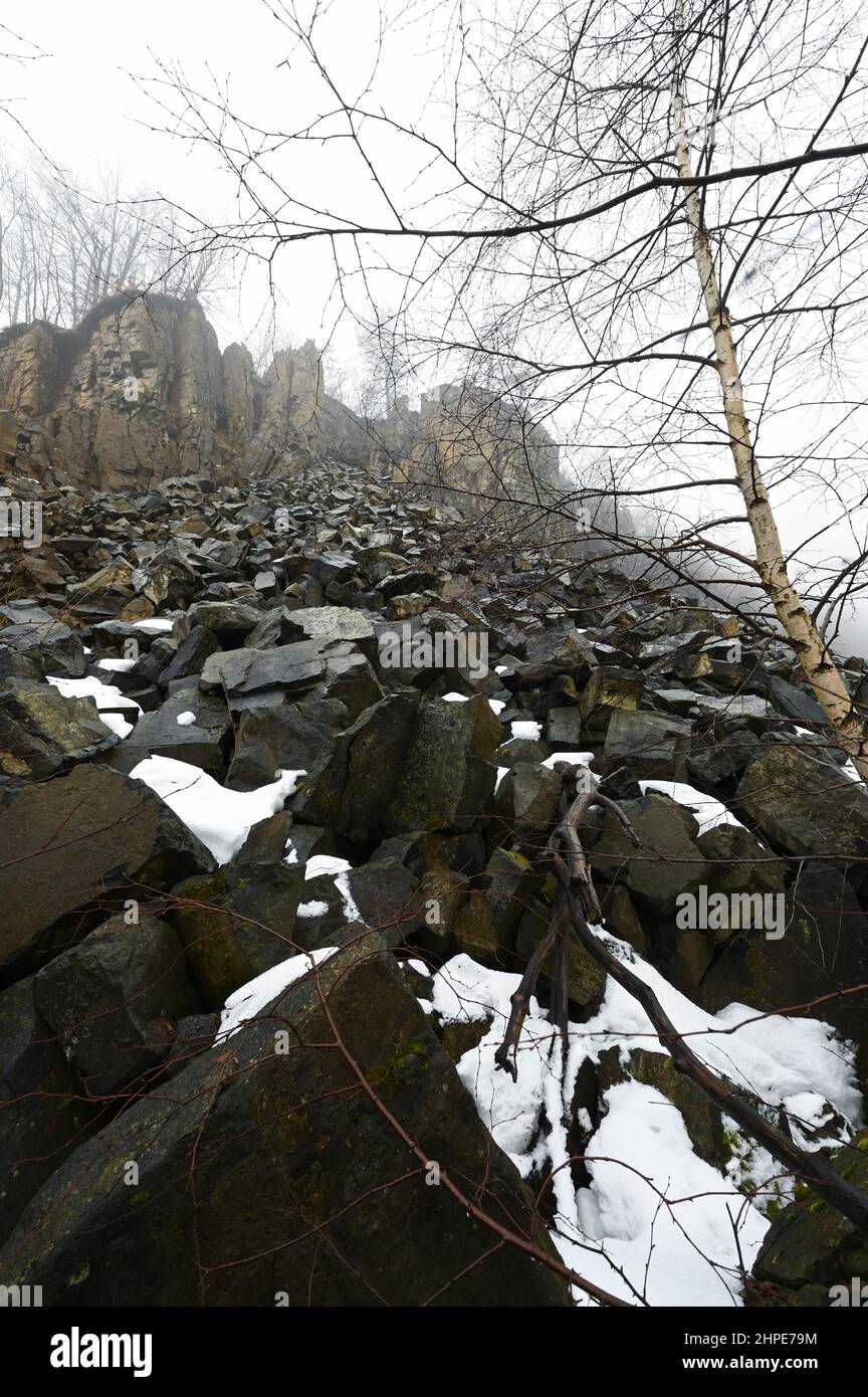 15 febbraio 2022, Hessen, Hoher Meißner: Avvolta nella nebbia è il muro di pietra di pietra dell'ex miniera di lignite a pozzo aperto di Kalbe sul versante orientale della Hohe Meißner. Un fuoco di giunco è stato bruciante qui per i secoli. Una reazione chimica fa sì che la lignite si infiammare da sola e smolga. In determinate condizioni meteorologiche, l'odore di zolfo può essere percepito a chilometri di distanza. (A dpa 'carbone incandescente nella Hohe Meißner: Fuoco di giunco è stato bruciante per secoli') Foto: Uwe Zucchi/dpa Foto Stock